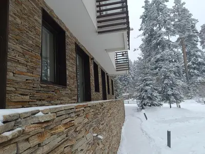 a brick building in the snow with a tree at Lyra Forest Apartment in Borovets