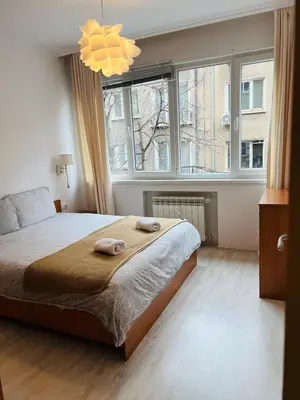 a bedroom with a bed and a large window at Sofiaway Central Apartment in Sofia