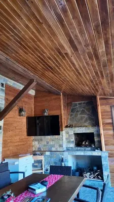 a living room with a stone fireplace and a flat screen tv at Къща за гости Гергана in Ribarica