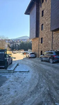 a parking lot with cars parked next to a brick building at Aurora Apartment in Bansko