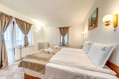 a large white bed in a room with windows at Комплекс Райковски Ливади in Pamporovo