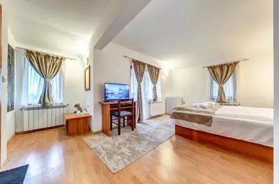a bedroom with a bed and a desk and windows at Комплекс Райковски Ливади in Pamporovo