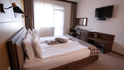 a bedroom with a large bed with a television on the wall at Комплекс Белите скали in Gaytaninovo