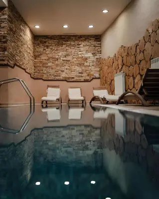 a swimming pool with lounge chairs and a brick wall at Private Studio in Royal Park in Bansko