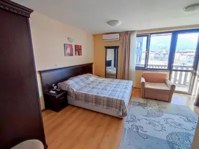 a bedroom with a bed and a chair and windows at Private Studio in Royal Park in Bansko
