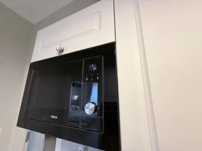 a microwave oven hanging on a wall in a kitchen at New top center cozy 3 bedroom apartment in Sofia
