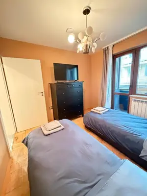 a bedroom with two beds and a tv and a dresser at New cozy 3 bedroom apartment 90m2 in Sofia