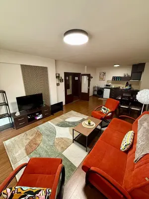 a living room with orange couches and a kitchen at Gino's place Home2Host in Bansko