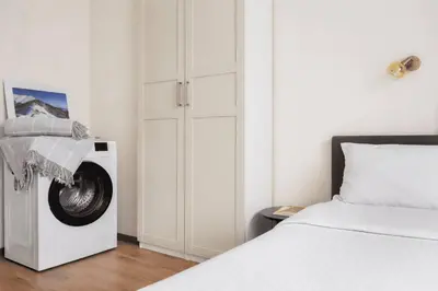 a white bedroom with a washing machine next to a bed at 2BR Apt - Parking - Central - 1st floor - ACs in Sofia