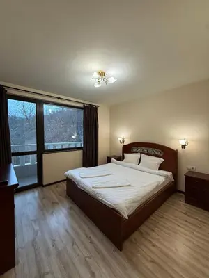 a bedroom with a large bed and a large window at Къща за гости GREEN HILLS in Beli Osŭm