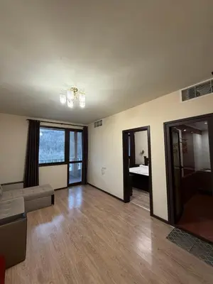 an empty living room with a couch and a window at Къща за гости GREEN HILLS in Beli Osŭm