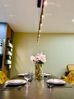 a table with plates and a vase of flowers on it at Regatta Park 1BR Exclusive Suite Parking Included in Plovdiv