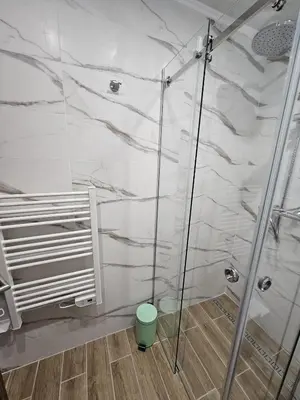 a shower in a bathroom with white marble walls at Predela Apartments with Spa in Bansko