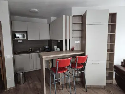 a kitchen with a table and two red chairs at Predela Apartments with Spa in Bansko