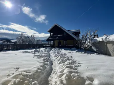 a snow covered yard with a house in the background at Mountain Family Guest House Rayovo in Rayovo