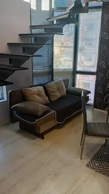 a black couch in a living room with windows at Кичук Париж in Plovdiv