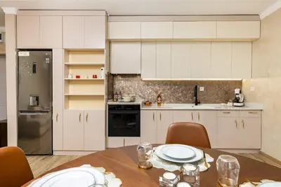 a kitchen with white cabinets and a table with chairs at Sunny Modern 1BR Retreat with Cozy Balcony in Plovdiv