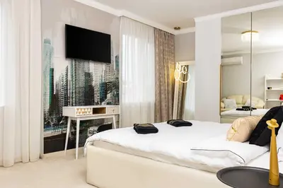 a white bedroom with a bed and a tv at Sunny Modern 1BR Retreat with Cozy Balcony in Plovdiv
