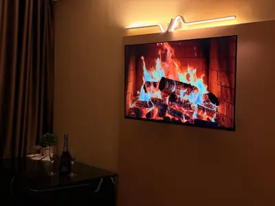 a flat screen tv hanging on a wall with a fireplace at Hotel NIRÁ in Sofia