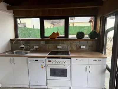 a kitchen with white cabinets and a sink and a window at Къща за гости Зорница in Ribarica