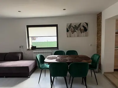a living room with a table and green chairs at Къща за гости Зорница in Ribarica