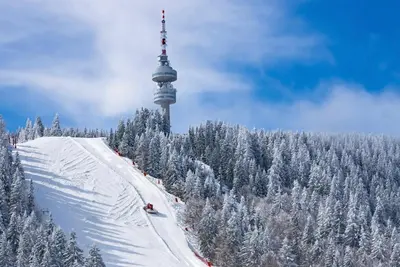 a ski slope with a tower on top of a mountain at Пампорово Mountain Lodge апартамент 46 in Pamporovo