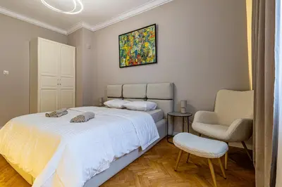 a bedroom with a bed and a chair and a painting at Grand Stamboliyski Residence in Sofia