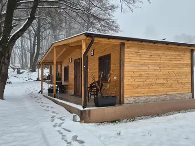 a wooden cabin with a porch in the snow at Бунгала ЛАГО