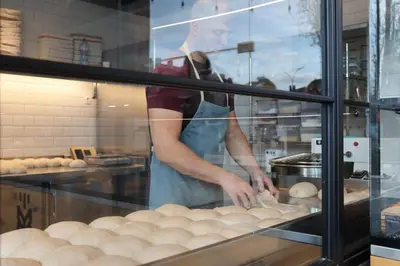 a woman is making bread in a bakery window at Blue Sky Penthouse with Parking Spot and Panorama Views in Sofia