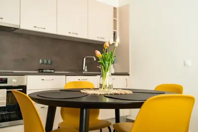 a dining room table with yellow chairs and a vase of flowers at Sunny Penthouse with Mountain Views and 180 degrees Terrace in Sofia