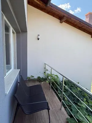 a balcony with a black chair and a window at The Walnut Nest in Sapareva Banya