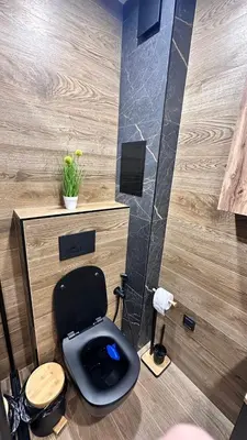 a bathroom with a black toilet in a room at Апартамент за гости Noa Sift in Velingrad