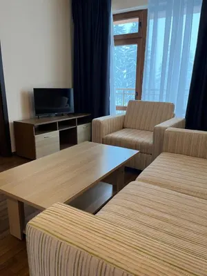 a living room with two chairs and a table and a tv at Hotel Rodope in Pamporovo