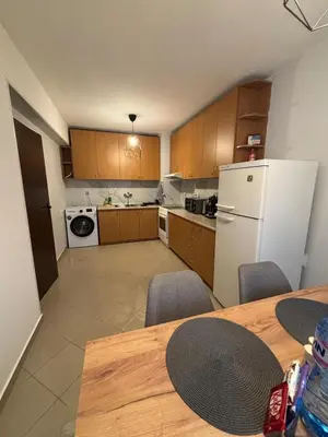a kitchen with a table and a white refrigerator at 2 Apartments 15 Seconds from Main street in Sofia