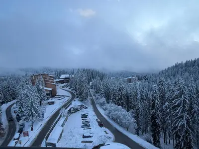 a snow covered road with cars and trees at Castle Inn Pamporovo 2 Bedroom Apartment in Pamporovo