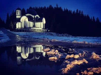 a building with a reflection in the water at night at Castle Inn Pamporovo 2 Bedroom Apartment in Pamporovo