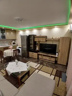 a living room with a television and a kitchen with a table at Estrella Apartment in Velingrad