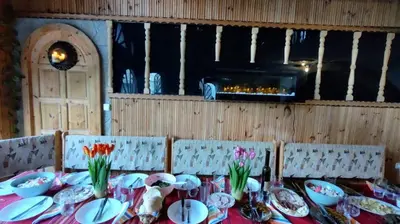a table with plates and bowls and flowers on it at Къща за Гости Слънце in Breze
