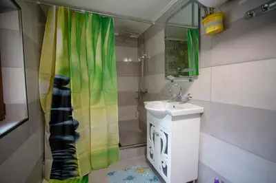 a bathroom with a shower curtain and a sink at Къща за Гости Слънце in Breze