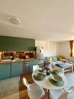 a kitchen and a living room with a table and chairs at Pirin Sense Apartment Home2Host in Bansko