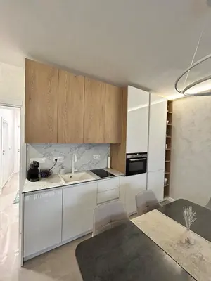 a kitchen with white cabinets and a sink and a table at Le bijou Lauta Forest in Plovdiv