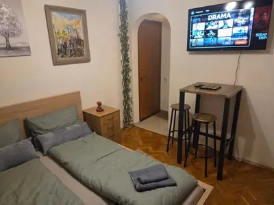 a bedroom with a bed and a table and a television at Three Vintage Apartments by NDK and Vitosha Blvd with Free Parking in Sofia