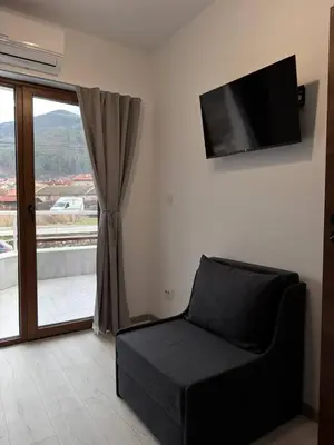 a living room with a couch and a flat screen tv at Bianca Guest House Sapareva banya in Sapareva Banya