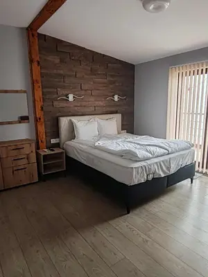a bedroom with a bed and a wooden wall at Guest House Vanessa 2 in Gulubovo