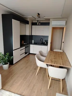 a kitchen with a wooden table and white cabinets at AMur Deluxe Apartment in Sofia
