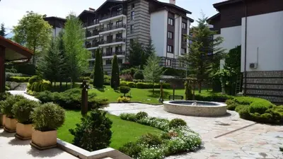 a large building with a garden in front of it at Your studio at Winslow Infinity in Bansko