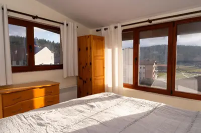 a bedroom with a bed and two large windows at Къща за гости Рилски рай in Samokov