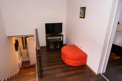 a living room with an orange chair and a television at Къща за гости Рилски рай in Samokov