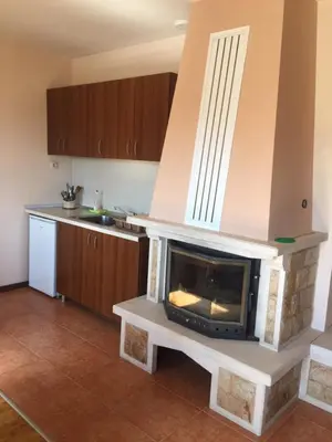 a living room with a fireplace in a kitchen at Вилно селище Баташки хан in Tsigov Chark