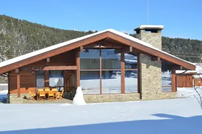 a log cabin with a table and chairs in the snow at Gostnici Holiday Home in Razlog